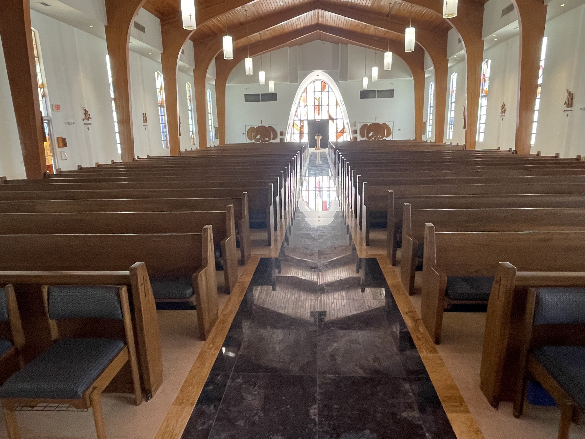 center aisle view photo Saint Michael the Archangel Catholic in Siesta Key, Florida after their pews were refinished by Woods Church Interiors