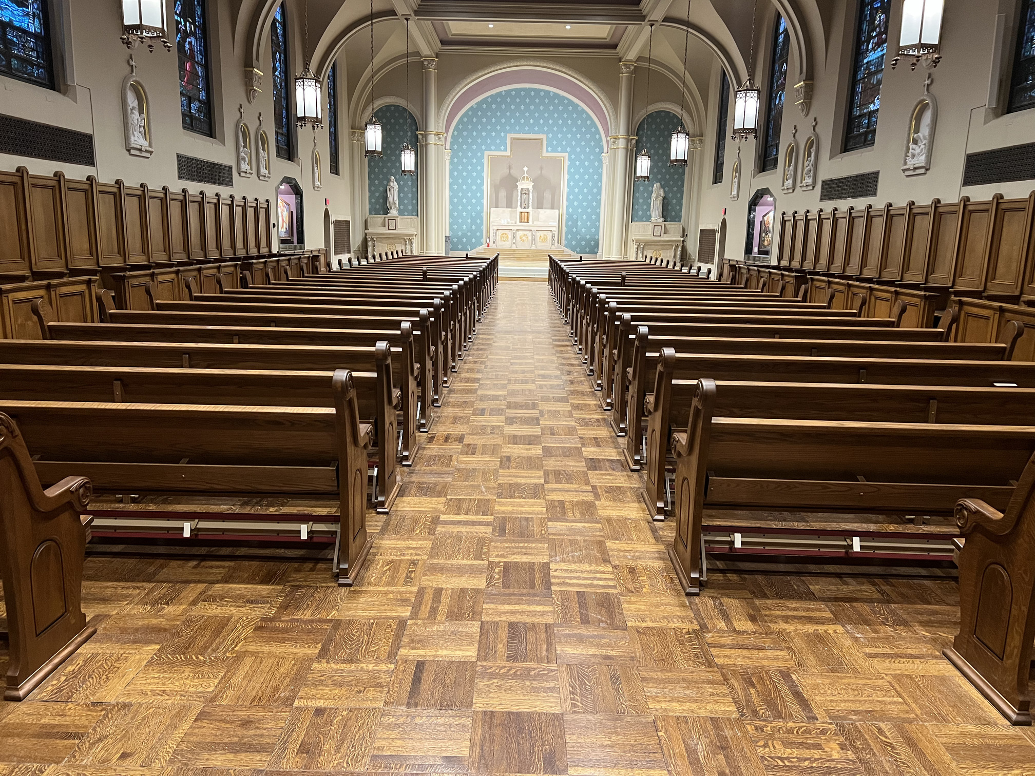 rear centter aisle view of newly refinished pews at Duchesne Academy in Omaha, Nebraska. Refinishing by Woods Church Interiors